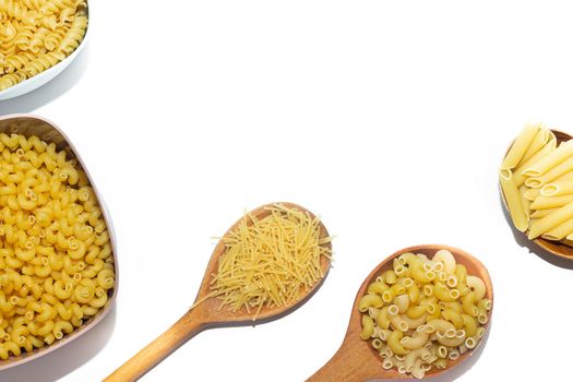 Macaroni several types in wooden spoons on a white background . Macaroni on wooden spoons . Macaroni on a white background. Article about the choice of pasta. Ingredients for the dish. Copy space . Isolated background. Food supply
