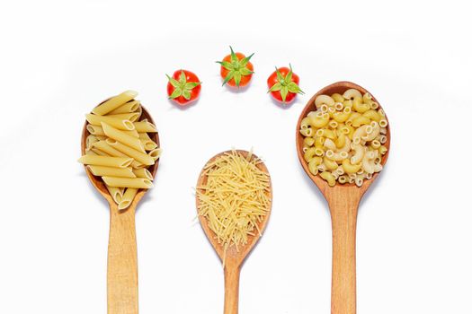 Macaroni several types in wooden spoons on a white background . Macaroni on wooden spoons . Macaroni on a white background. Article about the choice of pasta. Ingredients for the dish. Copy space . Isolated background. Food supply . Cherry tomatoes. Cooking pasta