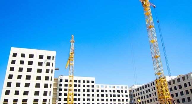 Construction of a multi-storey residential building . Construction crane . Block house. Building a house against the blue sky. copy space.