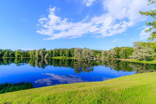 Summer evening in the Park with a lake. Summer landscape. nature of Russia. Well-maintained Park. Evening smoothness. The reflection in the water. Photo concept for printed products and puzzles