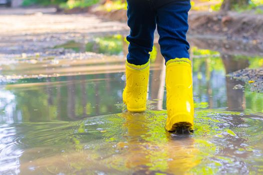 the boy jumps in a puddle. a boy in rubber boots. summer fun. game in town. children's entertainment. the article is about the holiday in the city . article about the choice of rubber shoes.