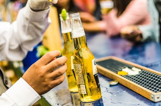 Lima, Peru - October 5th 2018: The waiter uncovers the ice cold beer for the guests at a midday party.