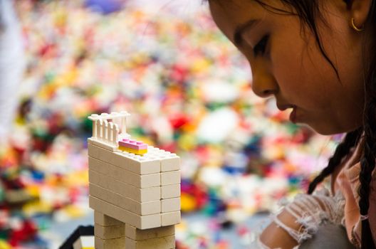 Little girl playing with colorful bricks at home or kindergarten. Closeup