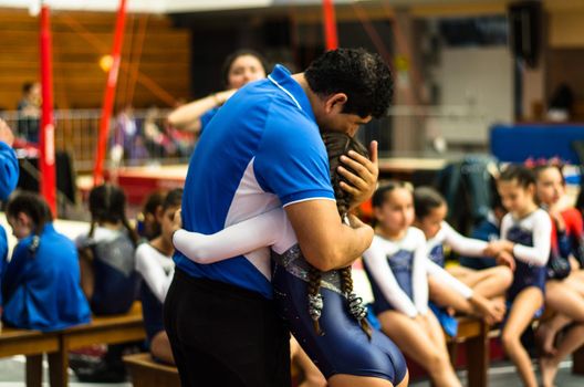 Gymnast girl congratulated by her instructor in the competition.