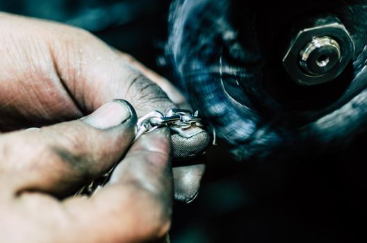 Jeweler working on silver chain in his workshop. Detail of silver polishing.