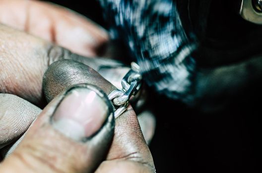 Jeweler working on silver chain in his workshop. Detail of silver polishing.