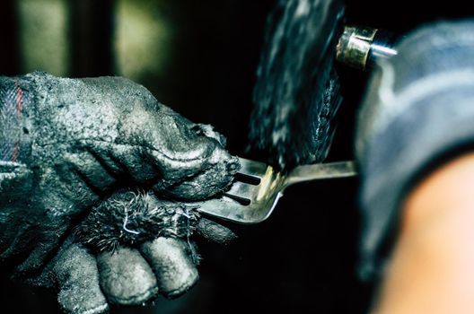 Jeweler working on silver fork in his workshop. Detail of silver polishing.