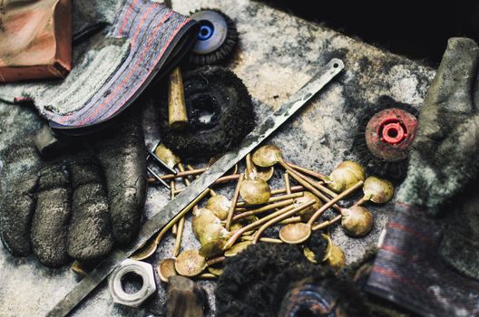 Top view of different goldsmiths tools on the jewelry workplace. Desktop for craft jewelry making with professional tools. Aerial view of tools over rustic wooden background.