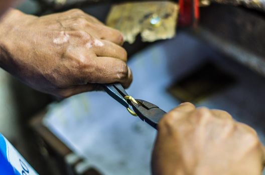 Hands of a jeweler working on a gold ring with a pliers