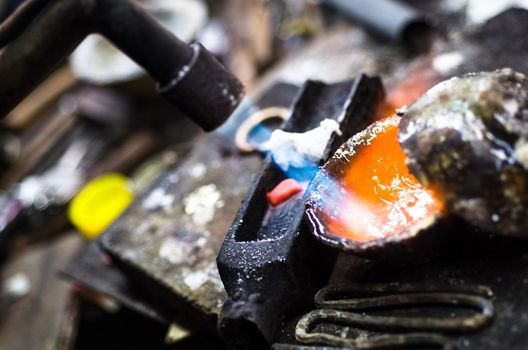 Craft jewellery making with professional tools. Macro shot. A handmade jewelry process, manufacture of jewellery. Melting silver