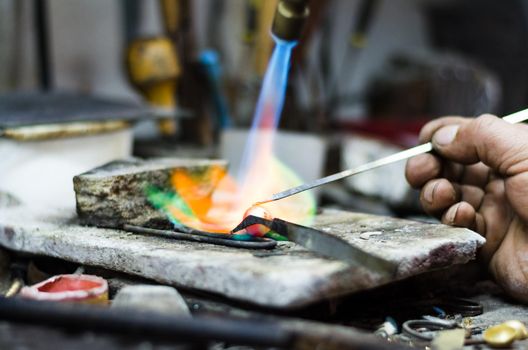 Master jeweler welding an ornament in a jewelry workshop. Image of hands and product close up.