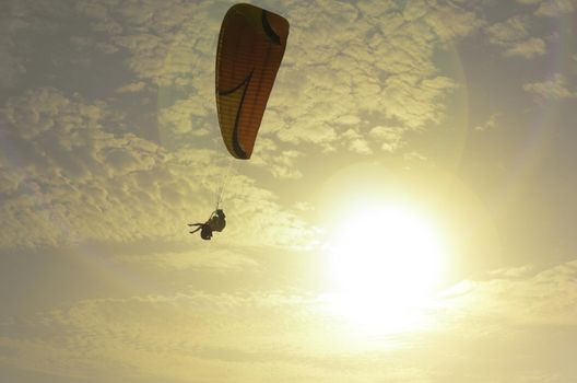 Silhouette of a couple of paragliders with sunset background.