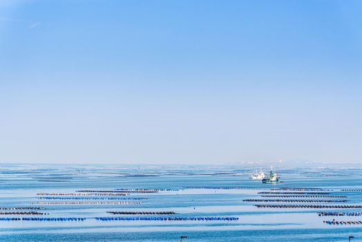 Beautiful nature landscape of the blue sea under the blue sky and floating buoys for mussel or Perna Viridis farming, boats and coastal fishing at Ko Loi or Koh Loy island in Chon Buri, Thailand