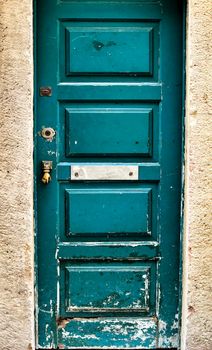 Old and colorful damaged wooden door with door knocker in Lisbon, Portugal.