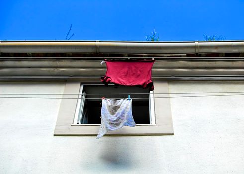 Old colorful typical facade in Lisbon with vintage wooden window and clothesline with hanging clothes