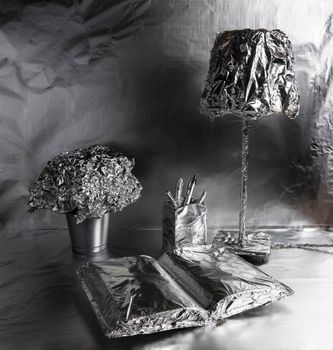 A lamp, a book and a plant pot wrapped in aluminum foil