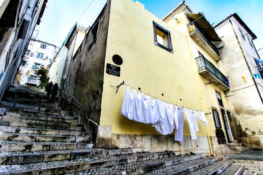 Narrow and colorful streets with majestic facades, windows and balconies of Lisbon city in Portugal in a cloudy day