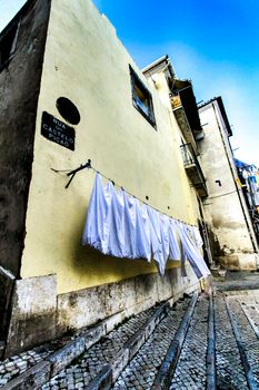 Narrow and colorful streets with majestic facades, windows and balconies of Lisbon city in Portugal in a cloudy day