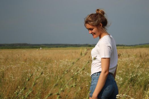 portrait of a blond charming beautiful woman in white t-shirt and jeans shorts in the wheat field .