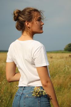 portrait of a blond charming beautiful woman in white t-shirt and jeans shorts in the wheat field .