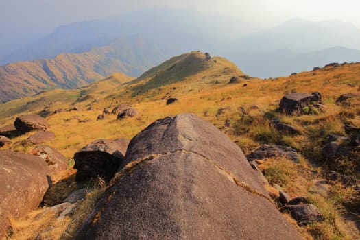 The mountain meadow has large round stones.