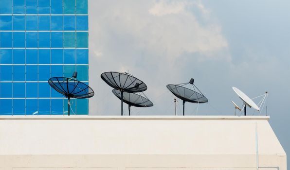 Satellite dish on top of a tall building with a background sky