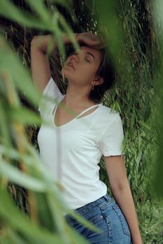 portrait of a flirty beautiful woman in white sport dress holding a tree branch in the tropical forest. Luxury resort.