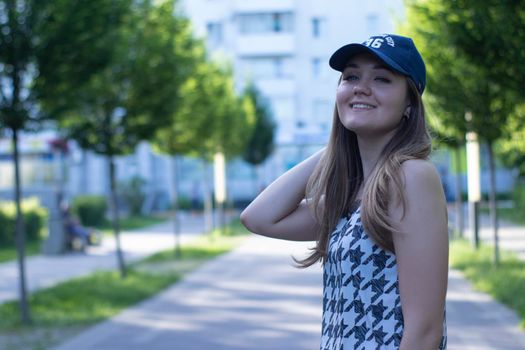 Pretty young blonde woman wearing a t-shirt, jeans shorts and cap. in a park. copy space. High quality photo