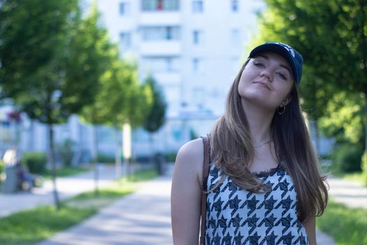 Pretty young blonde woman wearing a t-shirt, jeans shorts and cap. in a park. copy space. High quality photo