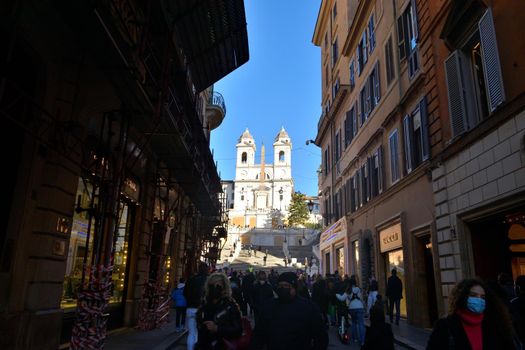 Rome, Italy, December 13th 2020. View of the Via dei Condotti and Trinita dei Monti during the Covid19 epidemic. Many people who wear protective face masks on their Christmas shopping stroll.