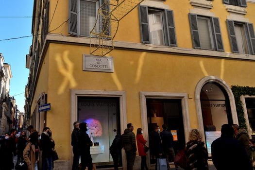 Rome, Italy - December 13th 2020: View of the Via dei Condotti during the Covid-19 epidemic. Many people who wear protective face masks on their Christmas shopping stroll.