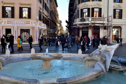 Rome, Italy - December 13th 2020: View of the Via dei Condotti during the Covid-19 epidemic. Many people who wear protective face masks on their Christmas shopping stroll.