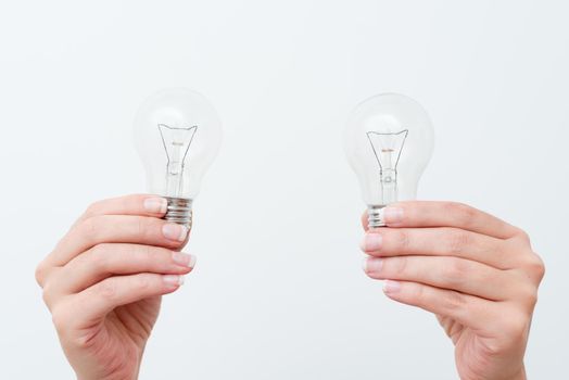 Woman Hands Holding Lamp Presenting Ideas For Project, Man Palm Showing Bulbs And New Technologies, Two Held Lightbulbs Exhibiting Another Opinion.