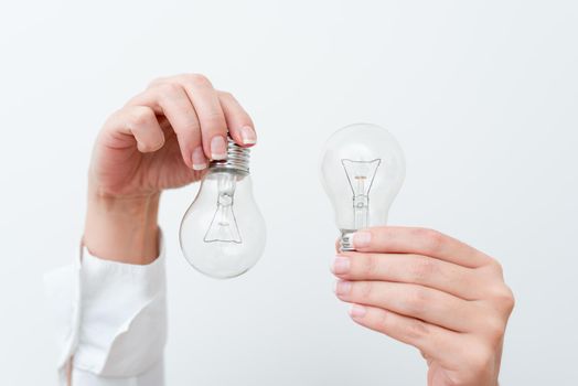 Woman Hands Holding Lamp Presenting Ideas For Project, Man Palm Showing Bulbs And New Technologies, Two Held Lightbulbs Exhibiting Another Opinion.