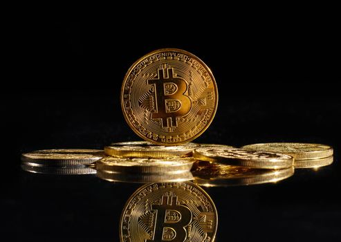 Leader in cryptocurrency Bitcoin BTC on a top of coins against black mirror surface. Closeup golden coin with bitcoin logo. А heap of decentralized digital currency. Crypto payment. Electronic money.