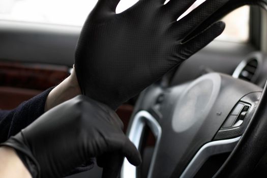 A man wears or removes protective gloves at the wheel.