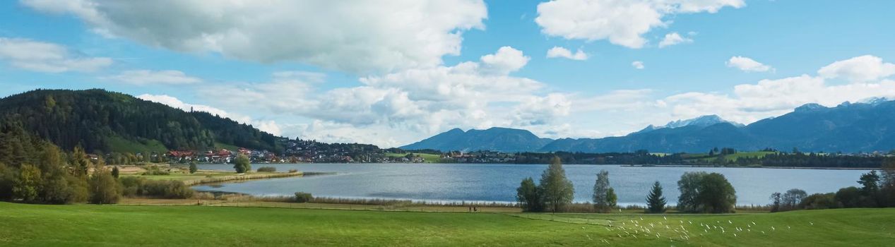 Beautiful nature of European Alps, landscape view of alpine mountains, lake and village on a sunny day, travel and destination scenery