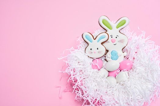 Delicious easter cookies in shape of bunny and eggs covered with colorful glaze. Styled pink pastel background. Festive symbols and traditions