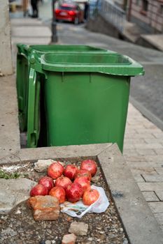 Ripe pomegranate fruits lie near the trash can. Help the homeless.