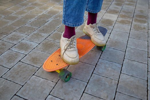 Children's feet in sneakers close-up on a skateboard on Pavement. Physical development of children.