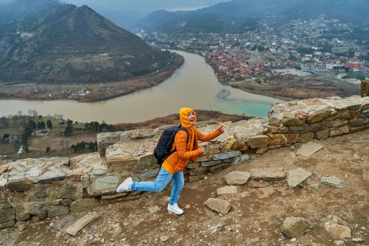 Young girl tourist rejoices posing against the backdrop of an amazing natural landscape. The confluence of two rivers in the city of Mtskheta in Georgia.