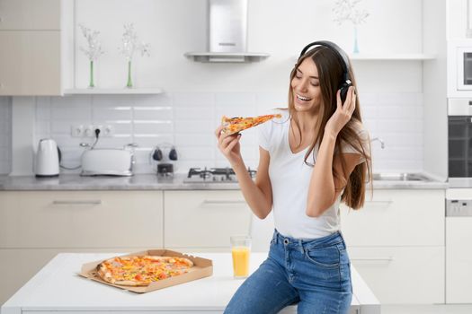 Close up of brunette woman relaxing with music and pizza at home. Concept of enjoying free time at home.