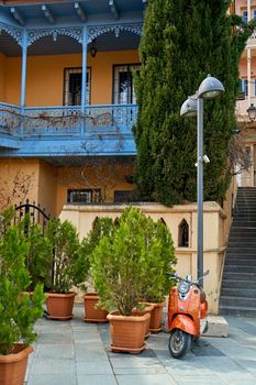 The architecture of the old district of Tbilisi. A retro moped is parked in front of a stylish old building. Tbilisi, Georgia - 03.16.2021