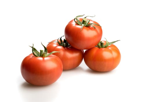 Four realistic looking fresh red tomatoes lying piled up isolated in a white background side view