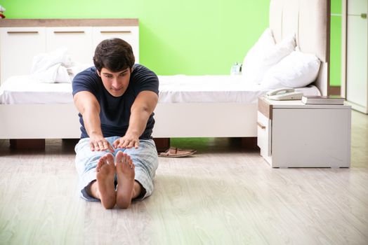 Young man in pajamas doing morning exercises 