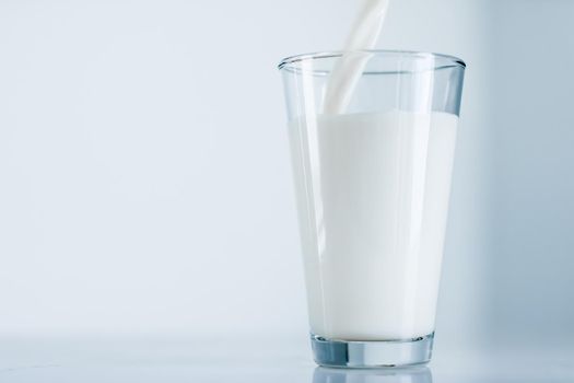 Dairy, healthy nutrition and breakfast concept - World Milk Day, pouring into glass on marble table