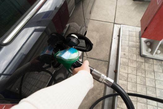 Female hand fill gasoline in a car with gas pump nozzle