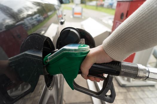 Female hand fill gasoline in a car with gas pump nozzle