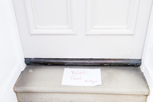 Doorstep with note saying wet paint warning sign