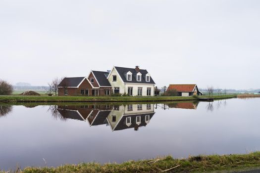 Dutch farmhouse at the side of a lake with reflection in the water near Amsterdam, the Netherlands